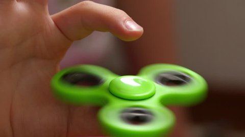 Close up footage of a green fidget spinner and a child playing with it...