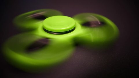 Close up and low angle footage of a green spinning fidget spinner...