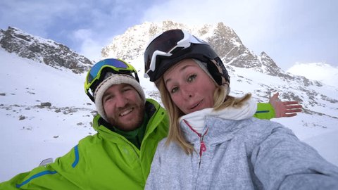 Young couple taking selfie on ski slopes while on vacation in Switzerland 
Couple ski selfie in the snow 