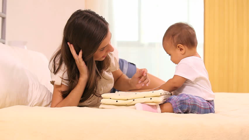 Beautiful mother play with her baby on the bed