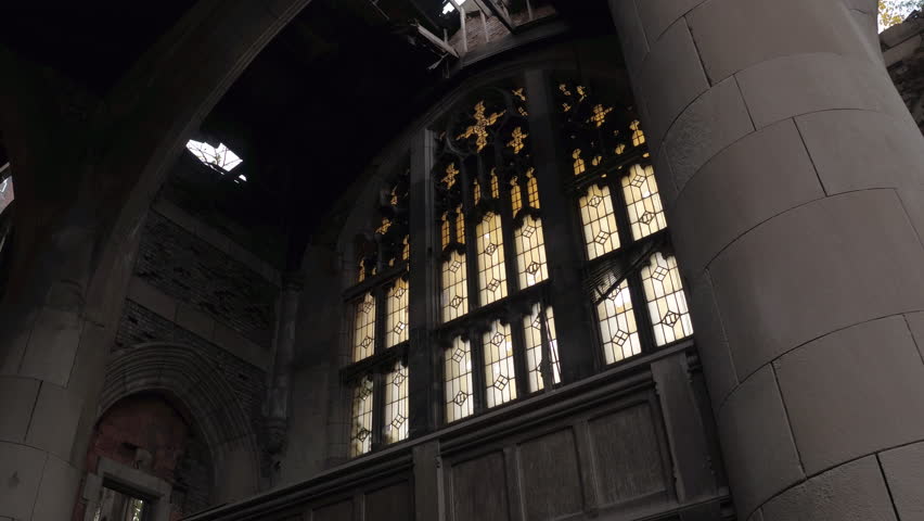 CLOSE UP: Majestic old gothic chapel in abandoned City Methodist Church, Gary Indiana, USA. Sun light coming through the broken roof and windows illuminating crumbling sanctuary in ruined cathedral