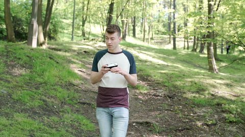 Man walking on pathway in the forest and doing photos on old camera, steadycam shot

