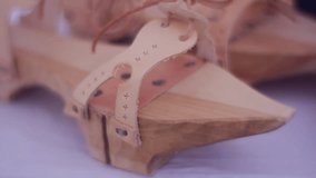 Wooden Shoes With a Sharp Socks. Thin Leather Straps Attached to the Shoes. This Shoes is Designed to Decorate a Home Interior in an Old Style. the Shoes Lie on a Wide Table in a Souvenir Shop. Video