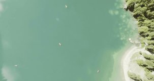 Overhead aerial drone flight establisher over lake with boats.Summer adventure journey in mountain nature outdoors. Travel exploring Alps, Dolomites, Braies Italy. 4k video above