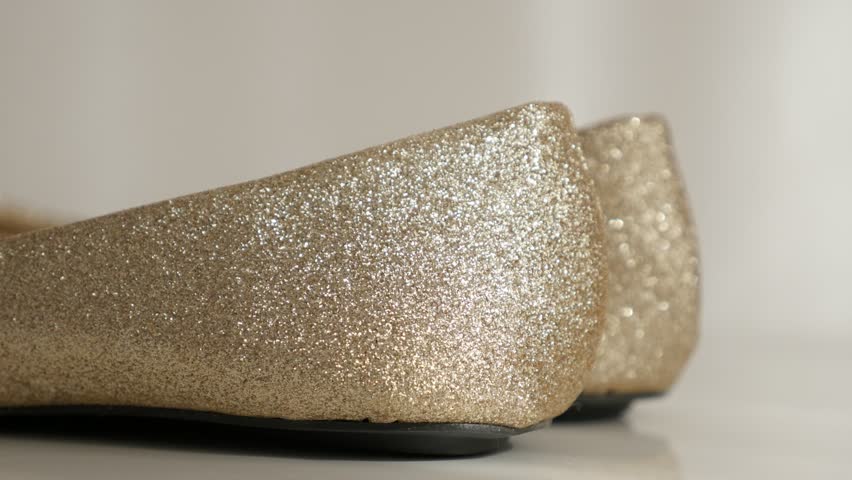 Back of golden ballet flats on white 4K 2160p 30fps UltraHD tilting footage - Close-up of prom night shiny sequined shoes slow tilt 3840X2160 UHD video