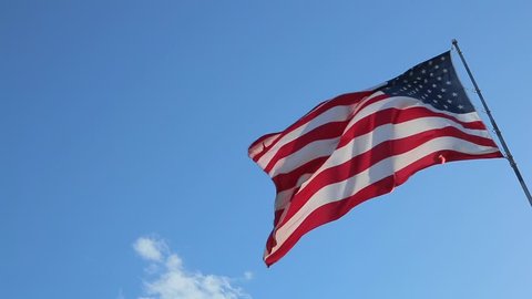 USA American Flag. Looking at flag pole with American flag waving. American Flag blowing in the wind with a blue sky background.