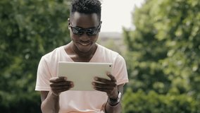 Black man using white tablet PC in park
