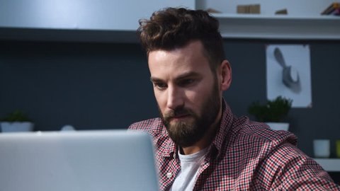 Portrait of young attractive bearded man architect working at a desk, use laptop in the office
