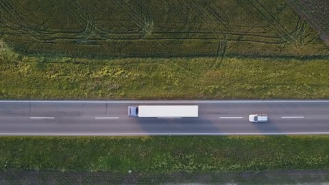 Aerial view of truck and cars on road through countryside, drone pov