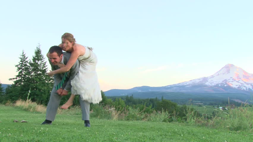 Model released bride jumping on her groom, laughing on their wedding day by