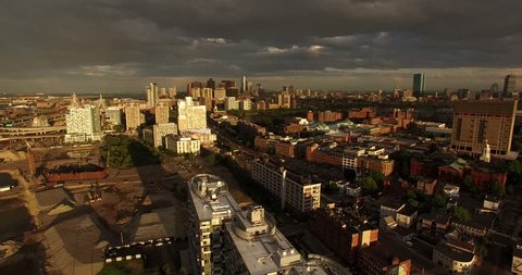 Aerial shot looking over construction site and gorgeous Boston skyline lit by setting sun