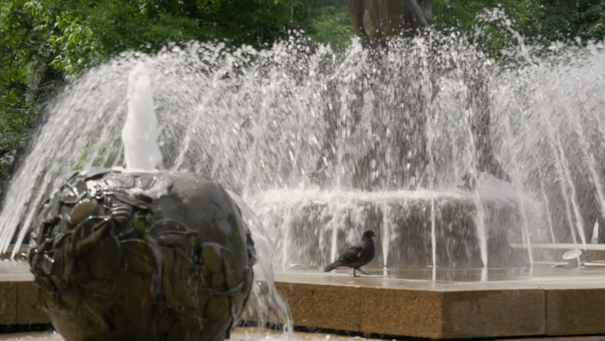 Beautiful fountain in the city park. The sun illuminates the splashes of water. Shining splash of water. Close up