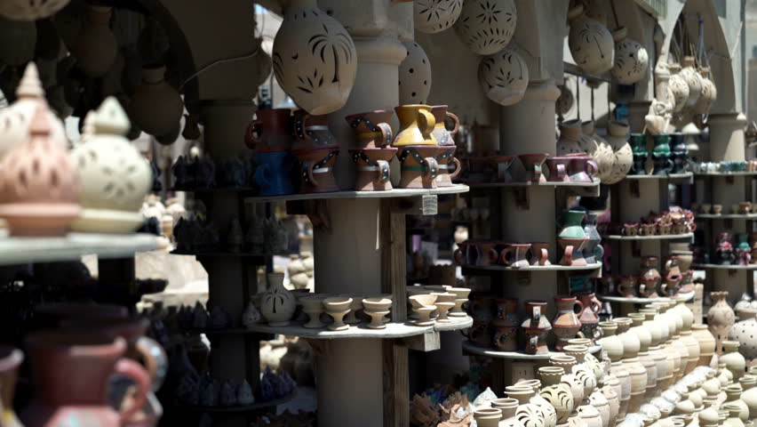 Young, beautiful woman checking souvenirs on flea market in Oman

