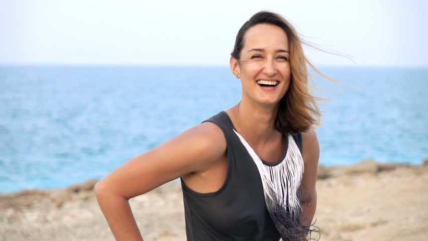 Portrait of happy, pretty woman standing on beach, super slow motion 240fps
