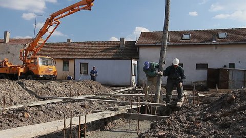 Zrenjanin, Vojvodina, Serbia - March 18, 2015: Construction workers are pulling large hose for concreting, directing the pump tube on right direction.