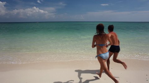 Young couple running into tropical sea