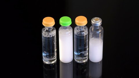 Four vials of insulin on a black background. Four ampoules for injection on a black background, close-up.