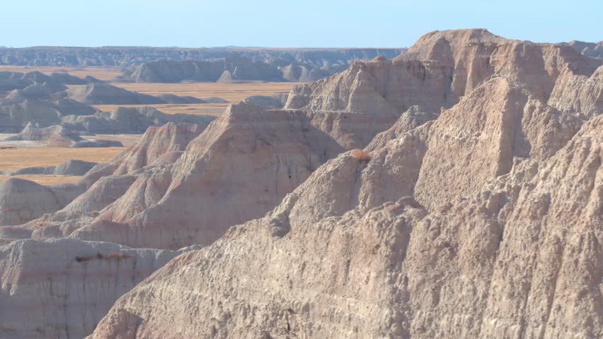 AERIAL: Amazing layered sandstone mountaintops against clear blue sky at Badlands National Park in South Dakota. Outer space landscape with eroded rocky mountain formations in Great Plains grasslands