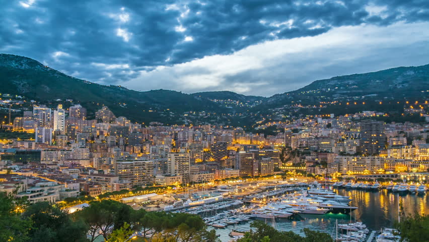 Monaco illuminated by night lights, luxury resort with elite yacht club, aerial