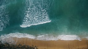 Aerial drone footage of huge waves rushing on shore.