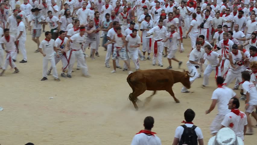 PAMPLONA - SPAIN - CIRCA JULY 2012: Revelers try to escape a wild cow in the
