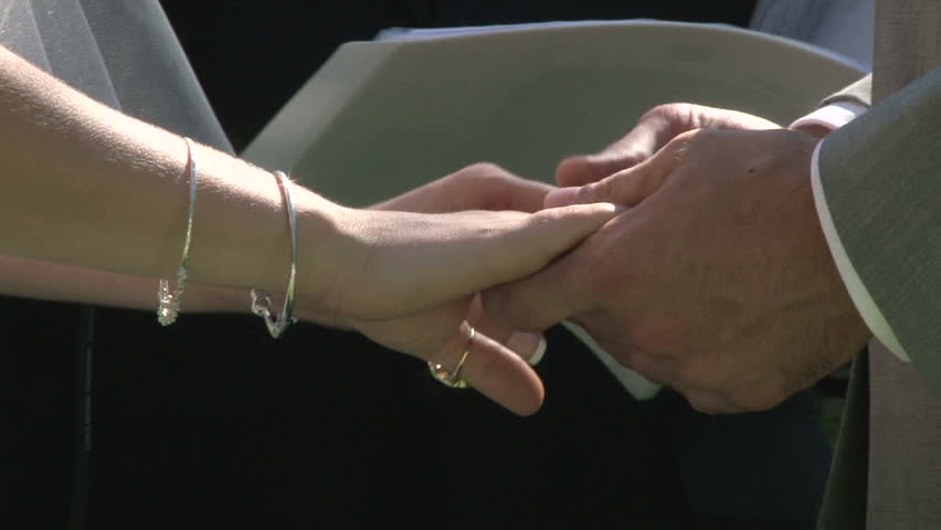 Bride and Groom holding hands on their wedding day during ceremony.