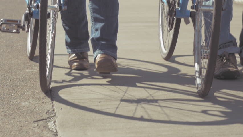 Low profile shot of two people pushing their bicycles