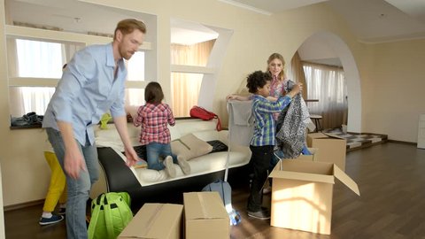 Family with children moving in. People unpacking boxes indoor.