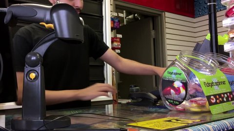 Coquitlam, BC, Canada - June 10, 2017 : Woman buying scratch tickets and taking receipt at check out counter inside Esso gas station convenient store with 4k resolution
