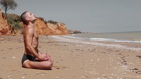 Young man in a Yoga lotus position on the deserted Wild Sea Beach storm before