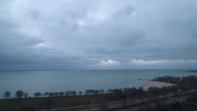 Cloudy morning time lapse in Chicago over Lake Michigan with white fluffy clouds moving across the sky and sun rays peaking through to the water
