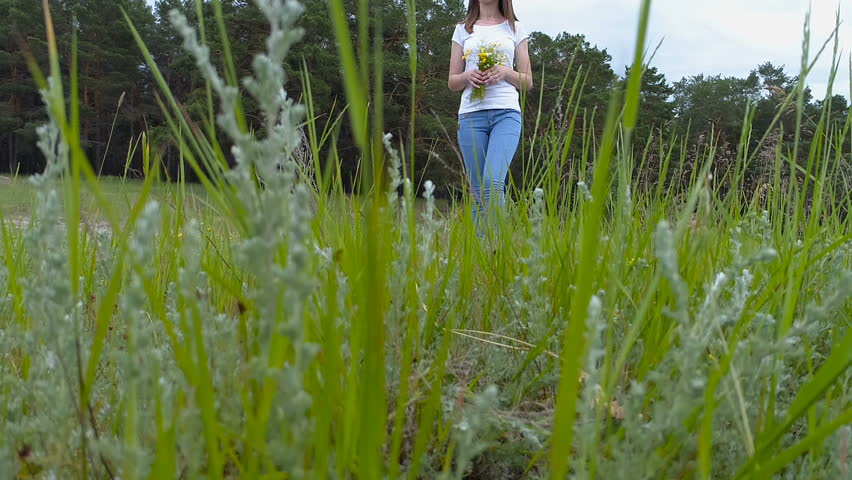 Young beautiful girl in dress goes on green field