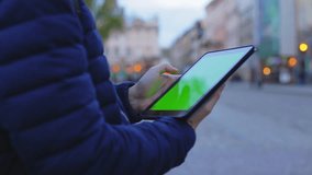 Man hand touching tablet computer surface touchscreen on street in Europe. Green screen for past your video 1080p