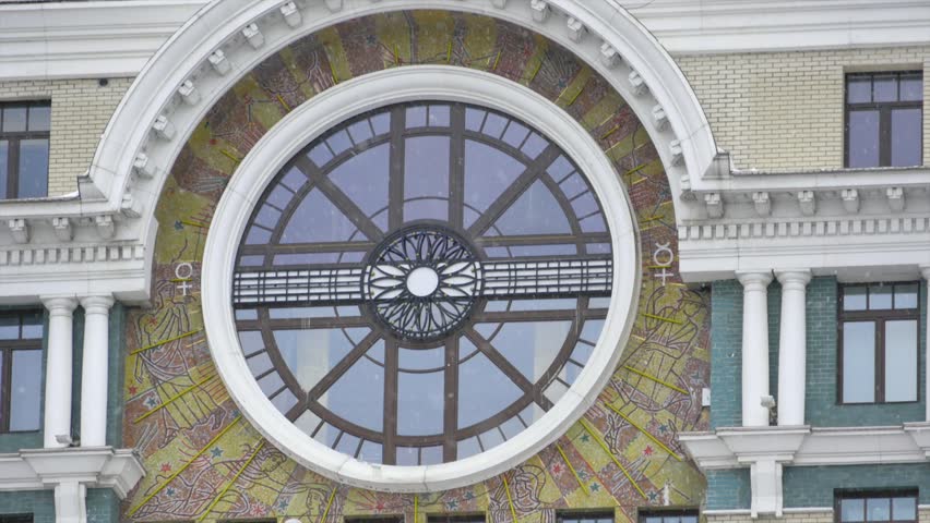 A round window of bautiful building and falling down snowflakes.