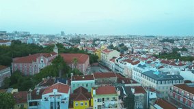 Slow fly over and aerial footage of the city and buildings in Lisbon, Portugal at sunset.