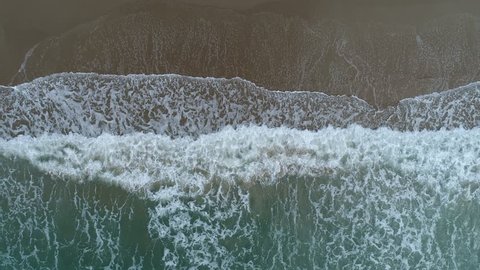 Aerial drone footage of ocean waves reaching shore. Beach on aerial drone top view.