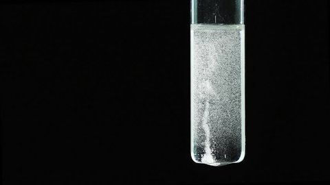 The interaction of zinc with a solution of sulfuric acid. Isolation of molecular hydrogen. Chemical reaction on a black background. The test tube.