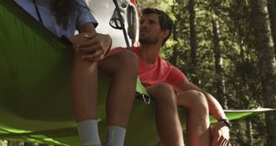 two smiling man and woman on hanging tent camping in sunny forest. Group of friends summer adventure journey in mountain nature outdoors.People travel exploring Alps, Italy. 4k slow motion 60p video