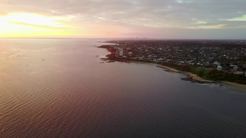 Aerial view at sunset above beach going towards melbourne slowly
