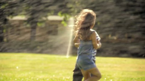 Kids are playing in a park with sprinklers Stock Video