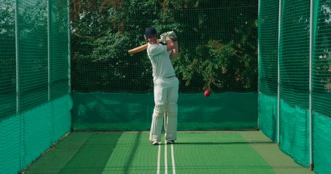 A cricket batsman strikes a cricket ball in the nets.