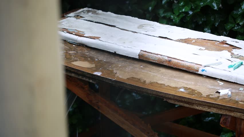 Drops of rain falling on shabby wooden table in yard 