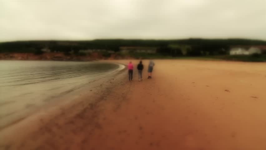 People walk along a sandy beach in a beautiful ocean cove