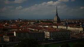 Timelapse video Torino (Turin, Italy) skyline with the Mole Antonelliana towering over the buildings. Wind storm clouds over the Alps in the background.