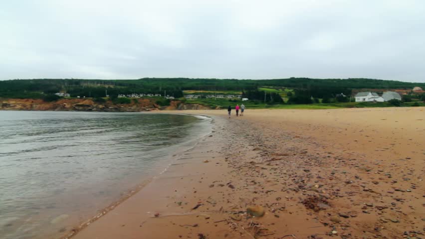 A family walks along a sandy ocean beach