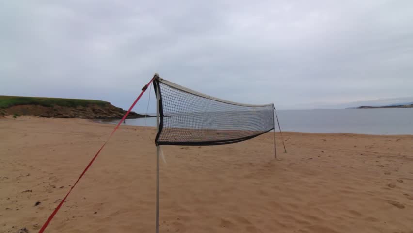 A volleyball net set up on a sandy ocean beach