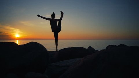 Healthy young woman practicing yoga on the cliff in the nature dawn slow motion
