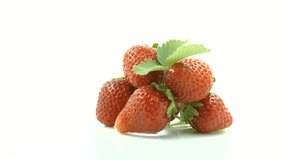 Strawberry rotation over white Background. Ripe fresh and juicy Strawberries with leaf and blooming flower close-up. 4K UHD video 3840X2160
