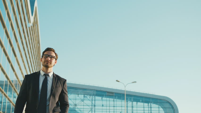 Happy attractive businessman walking outside near big office building and looking around. Man looking satisfied and happy Day . ,Young manager, technology, executive,  male person Success Concept Royalty-Free Stock Footage #27766087