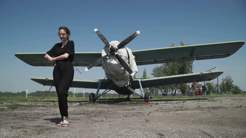 Woman pilot portrait in front of plane bomber. in a black combo standing in front of a huge air propeller